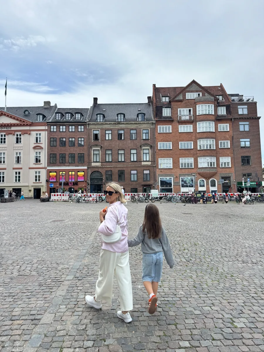 Jane ja lapselaps käest kinni üle munakivise väljaku Kopenhaagenis