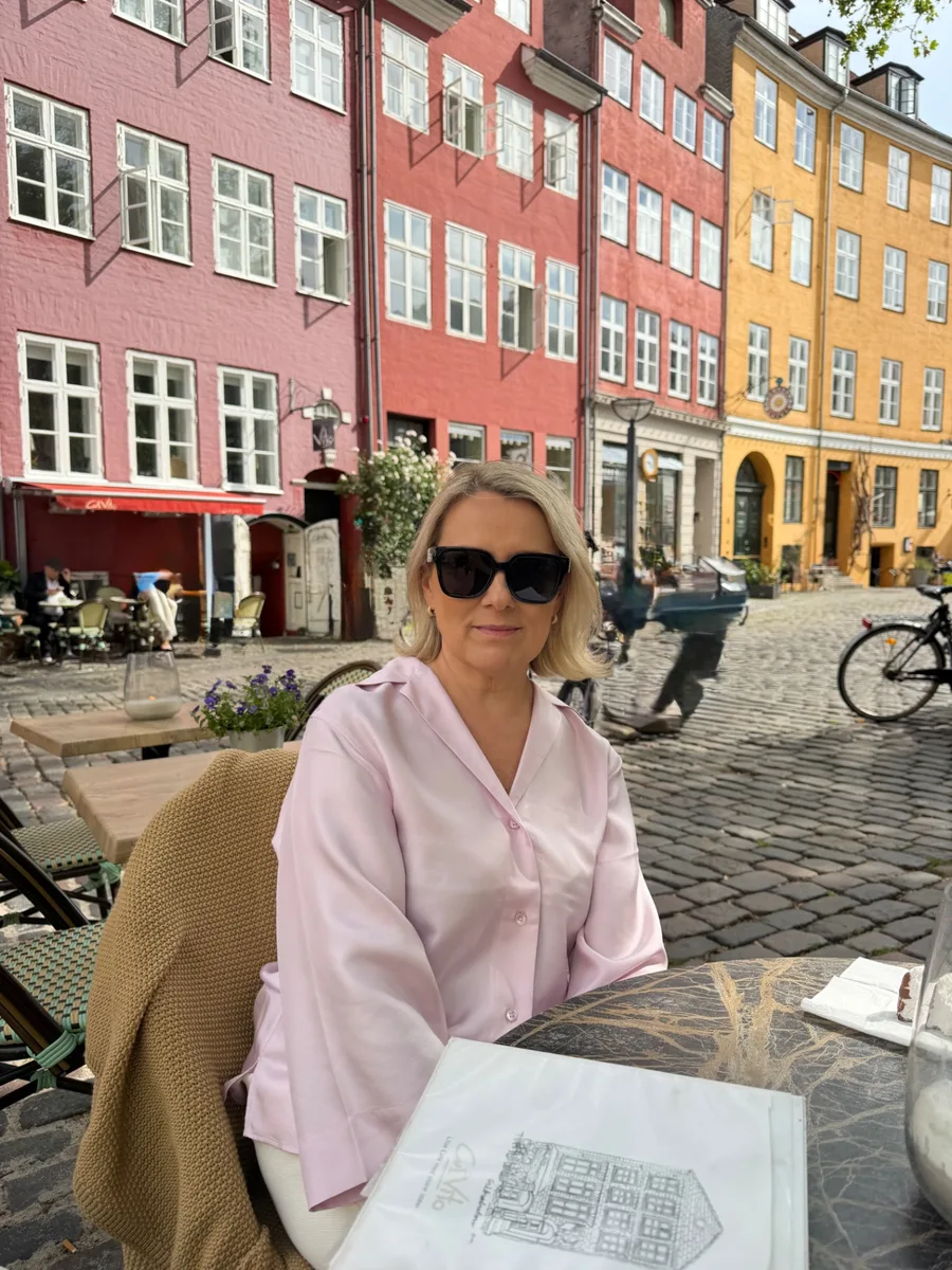 Jane istumas välikohviku laua taga Nyhavni värviliste majade ees